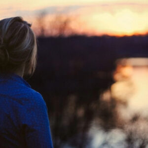 An human trafficking survivor looks out over a lake.